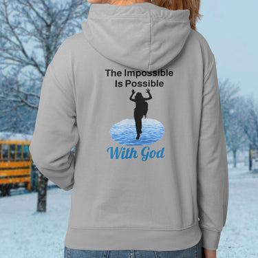 Gildan youth zip-up hoodie with “Impossible Girl” design featuring a girl walking on water and uplifting message, Christian apparel made from soft preshrunk fleece, ideal for cooler weather and faith-forward style, girl in gray hoodie